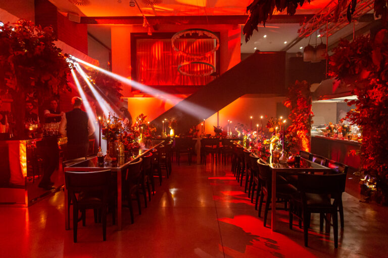 White pinspot lighting over seating area with warm ambient uplighting