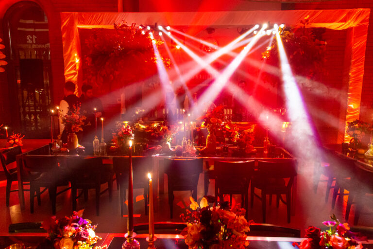 White pinspot lighting over seating area with warm ambient uplighting