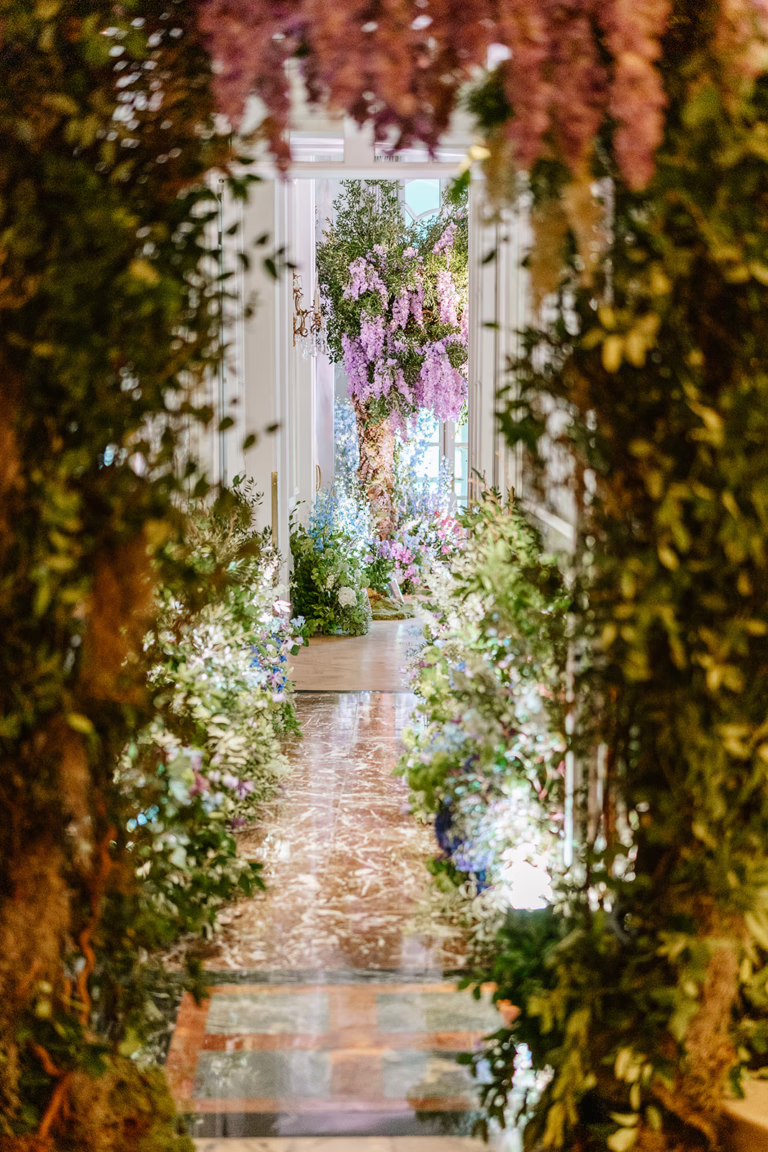 Illuminated hallway filled with floral arrangements into the wedding reception